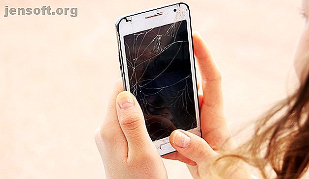 Une femme tenant un smartphone cassé